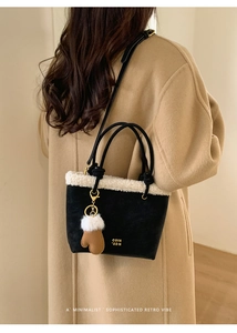 Detail of black suede bucket bag with white faux fur trim and creative mitten charm