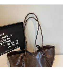 Detail of dark brown leather tote showing long shoulder straps with knot design and snap