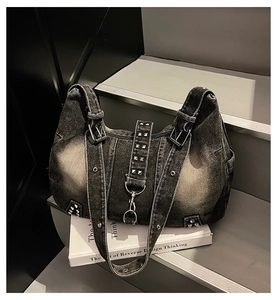 Detail of black washed denim tote bag featuring silver studs and metal buckle details