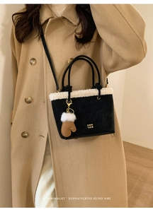 Detail of black matte bucket bag with white faux fur trim and gold lettering logo