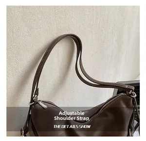 Close-up of dark brown leather tote bag with double stitching and silver metal buckle