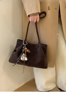 Detail of dark brown tote bag featuring leopard print charm and plush heart pendant