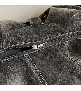 Detailed macro view of smooth silver metal zipper on dark gray washed denim fabric