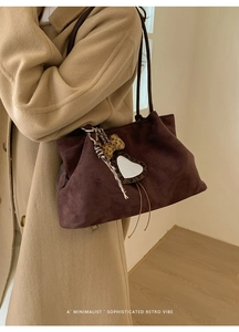 Detail of dark brown suede tote bag with heart mirror charm and fringe tassel