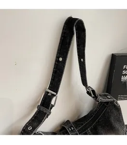 Detail of adjustable washed denim shoulder strap with silver buckles and punk studs