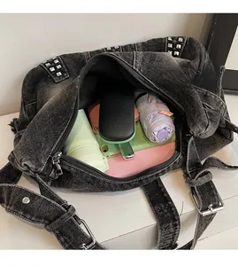 Top view of spacious interior of black washed denim bag with silver studs and daily essentials