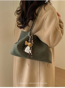 Detail of dark green suede tote bag with leopard bow charm on model shoulder