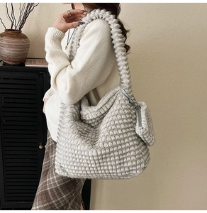 Detail of grey plush shoulder bag featuring soft textured squares and a matching mini pouch