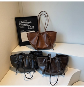 Detail of minimalist leather tote bags with long handles and side drawstring knots
