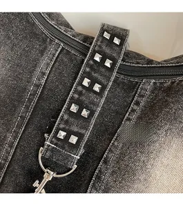 Close-up of washed denim tote with silver metal studs and heavy-duty lobster clasp
