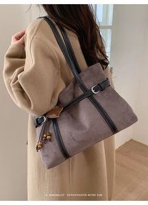 Detail of grey suede tote bag with black leather straps and heart pendant charm