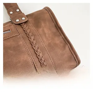 Macro detail of brown leather travel bag showing fine stitching and braided trim
