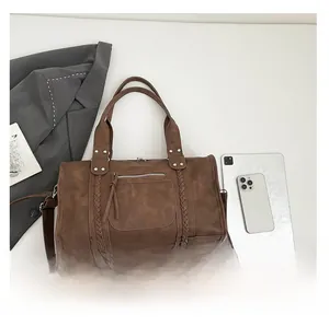 Brown retro boston bag with braided straps shown alongside a tablet and a smartphone