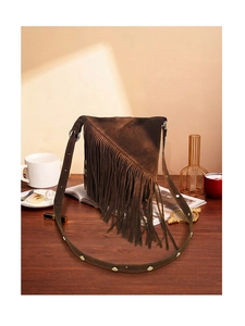 Detailed view of brown suede fringe bag with metallic studs on vintage wood surface