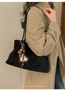 Detail of black suede tote bag with heart mirror charm and leopard print tassel accessory