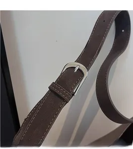 Close-up of dark brown leather shoulder strap with silver buckle and fine stitching details