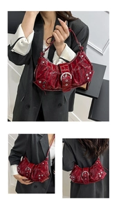 Detail of red crescent shoulder bag with glossy crocodile texture and silver metal rivets
