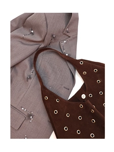 Close-up of brown suede tote bag with golden metal eyelets and magnetic closure