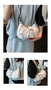 Detail of white crocodile pattern shoulder bag with silver studs and large metal buckles