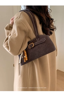 Detailansicht der braunen Retro-Schultertasche mit Perlenanhänger und goldener Schnalle