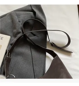 Detail of adjustable shoulder strap and silver metal buckle on a brown leather bag