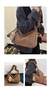 Detail of brown pleated cloud shoulder bag with matte finish and teddy bear charm