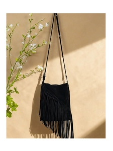 Detail of black suede crossbody bag featuring long fringe tassels and silver studded strap