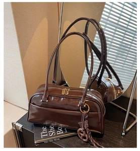Detailed view of deep brown polished faux leather bowling bag with gold zippers and long straps
