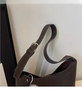 Detail of adjustable shoulder strap and metal buckle on dark brown square crossbody bag