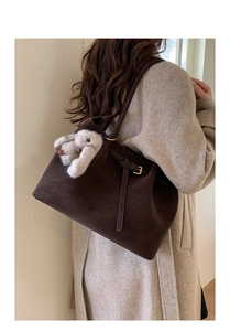 Detail view of deep brown tote bag featuring textured finish and cute rabbit charm