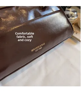 Close-up of a vintage brown leather pillow bag with gold lettering and soft texture