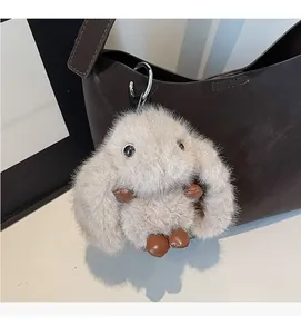 Detail of soft beige plush rabbit charm with brown leather accents on hobo bag