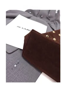 Detailed close-up of dark brown suede tote bag bottom showing sturdy structure and stitching