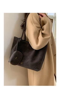 Detalle de bolso tote marrón oscuro con monedero a juego y logotipo dorado de moda