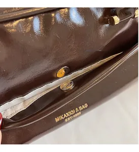 Detail of dark brown glossy leather texture with golden hardware and brand logo