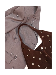 Close-up of coffee suede tote bag with golden eyelets and grey blazer detail