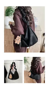 Detail view of black pleated cloud bag with a cute brown plush bear charm pendant