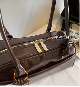 Detail of smooth gold double zippers and hardware on a brown leather Boston bag