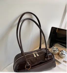 Detail of dark brown wax leather pillow bag with dual zippers and long handles