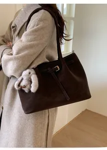 Détail du sac cabas en daim marron foncé avec fines bretelles et breloque lapin en peluche