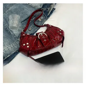 Detail of dark red crocodile pattern hobo bag with silver rivets and metal buckle