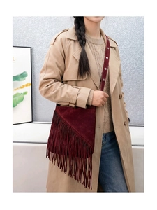 Detail of burgundy faux suede crossbody bag with long asymmetric fringe and slim strap