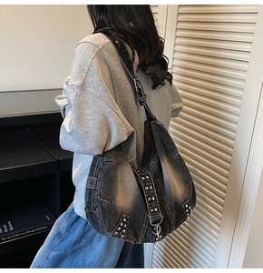 Detail of silver rivets on washed black denim tote bag with adjustable shoulder strap