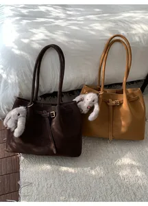 Détail de grands sacs fourre-tout en faux daim marron et caramel avec charms lapin