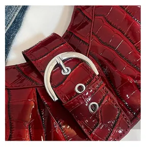 Close-up of glossy deep red crocodile pattern leather strap and silver metal buckle