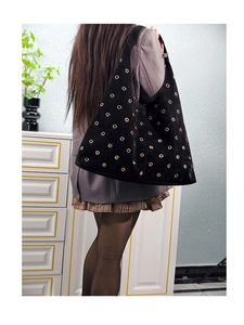 Detailed view of the black suede hobo bag with gold metal eyelets on a model