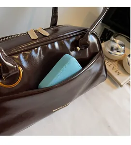 Close-up of deep brown oil wax leather bag featuring an external pocket and gold hardware