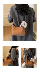 Detail of brown faux leather hobo bag with cute white plush rabbit charm on strap