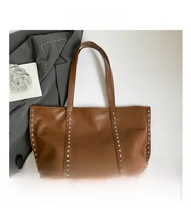 Detailed close-up of silver rivet accents on the brown leather tote bag exterior