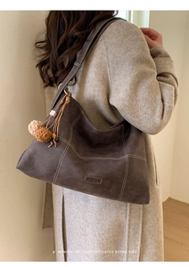 Detalle de bolso tote marrón retro con costuras blancas en contraste y adorno de peluche